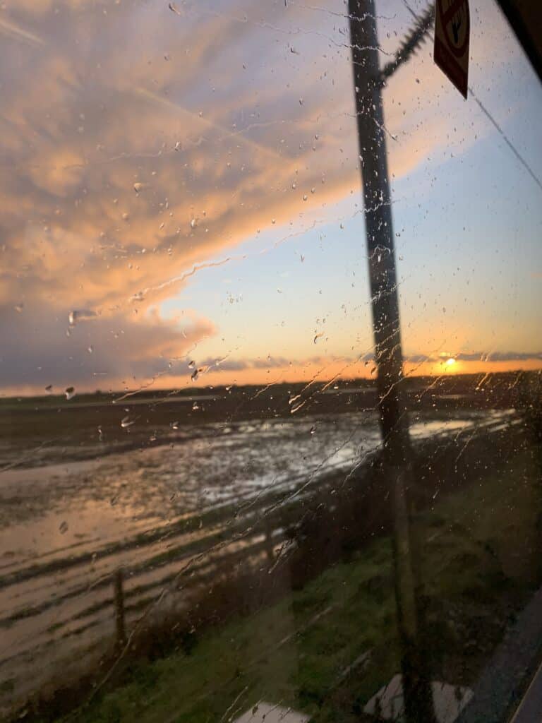 A picture of a blazing sunset with clouds, taken through a train window as I went to see a friend.