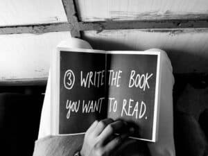 someone reading a book with a book idea, “write the book you want to read” written on its open pages.
