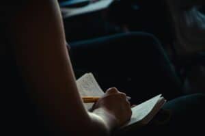 A shot of an anonymous person writing in a notebook, to advertise my new course, Write Who You Are.
